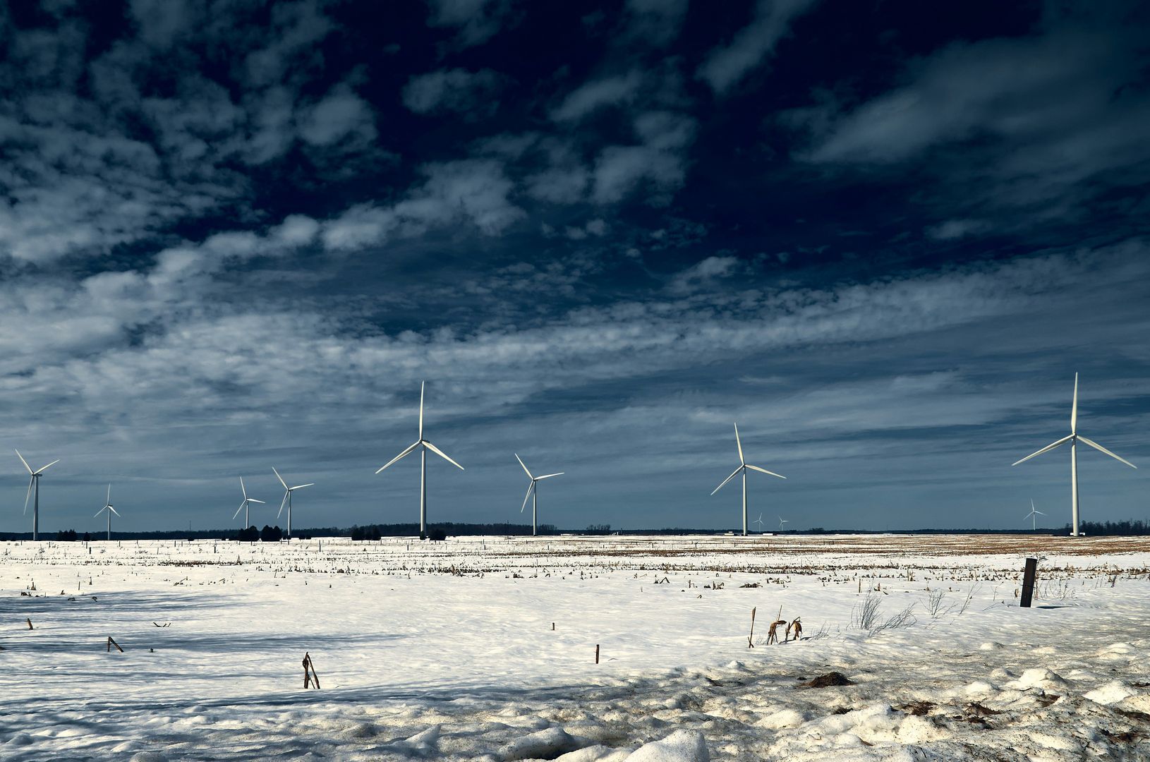 Beschneites Feld mit Windrädern im Hintergrund