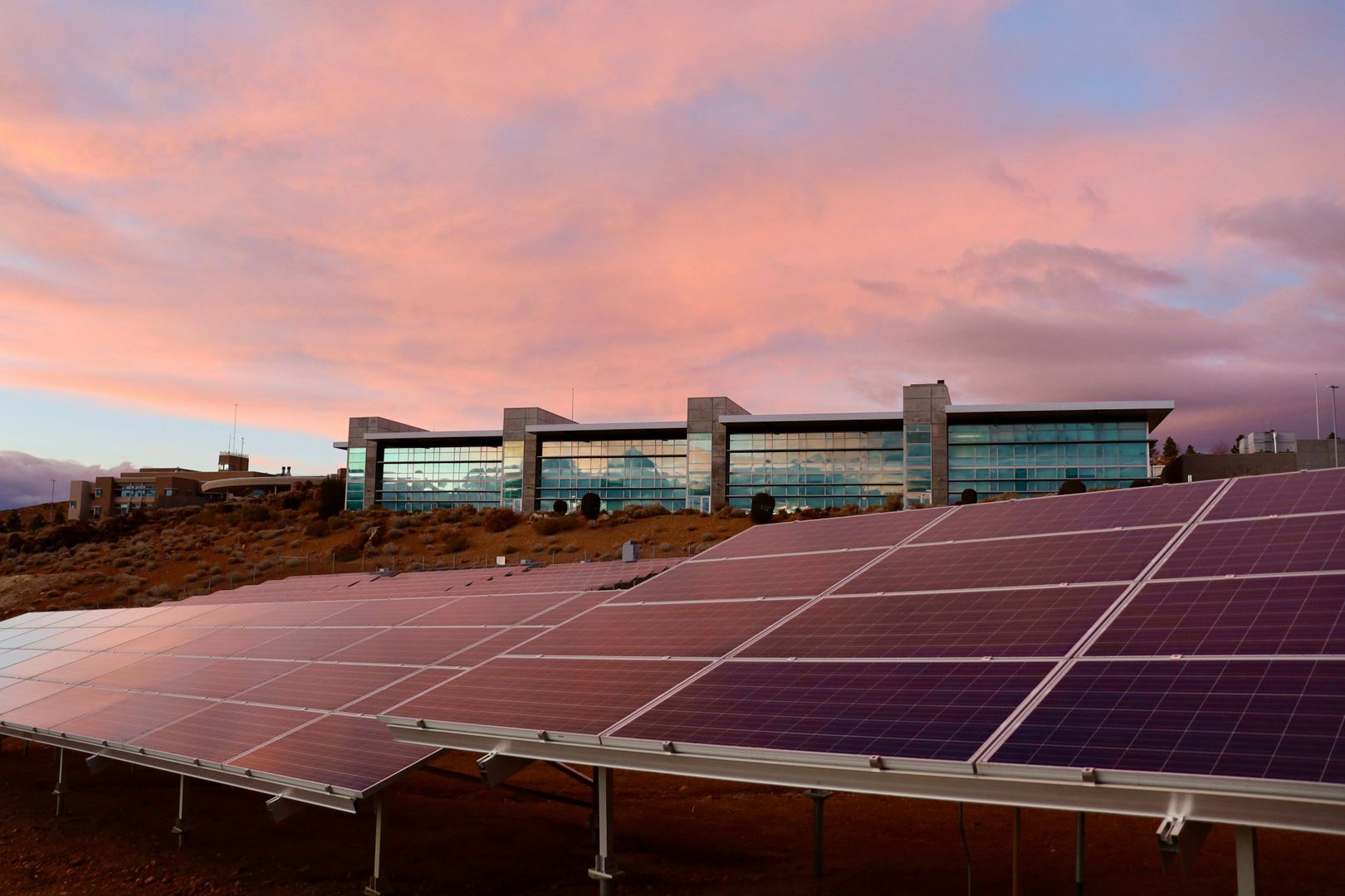 Im Vordergrund sind Solarpanele im Licht des Sonnenuntergangs